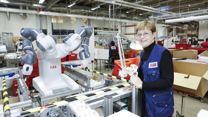 Pirjo Metso työskentelee YuMi-robotin kanssa ABB:n Porvoon tehtaalla.