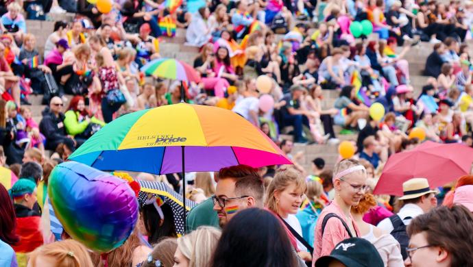 Värikkäitä sateenvarjoja ja paljon ihmisiä seisomassa Senaatintorilla ja istumassa Helsingin tuomiokirkon portailla.